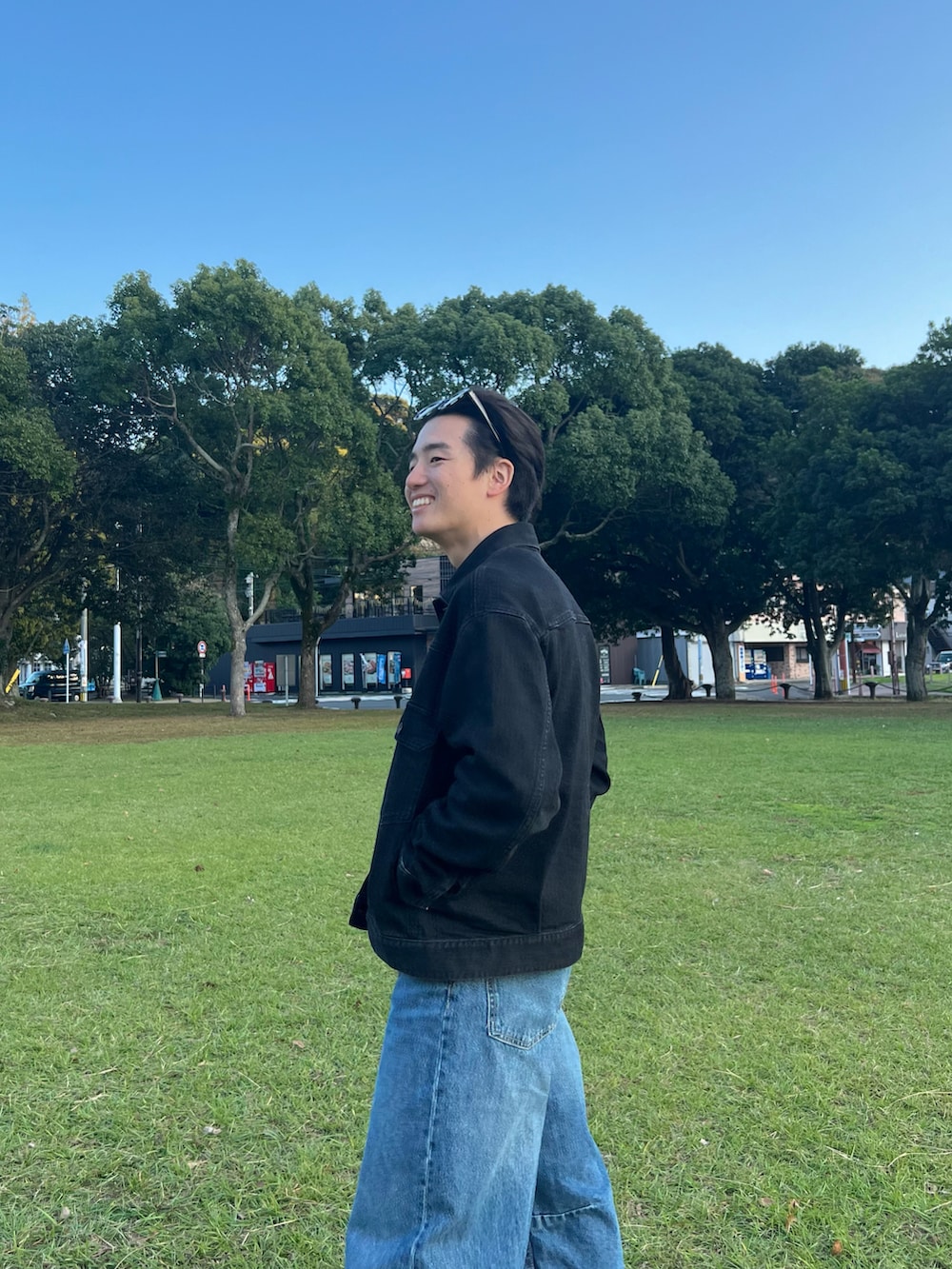 ブラック系のデニムジャケット、ブルー系のデニムパンツ、グレー系のスニーカーを着用したメンズの春コーディネートの3枚目の写真