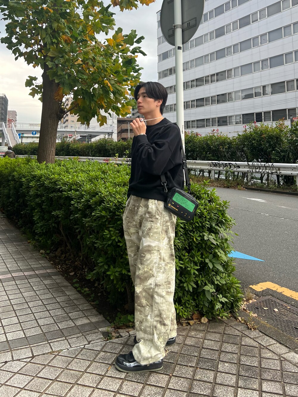 ブラック系のスウェット、グリーン系のチノパンツ、ブラック系のスニーカーを着用したメンズの春コーディネートの3枚目の写真