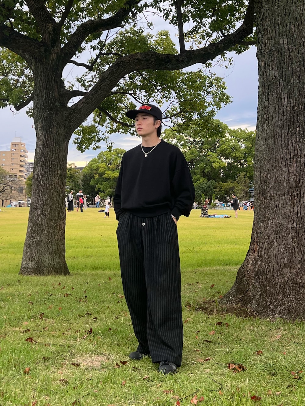 ブラック系のスウェット、ブラック系のスラックス、ブラック系のスニーカーを着用したメンズの春コーディネートの2枚目の写真