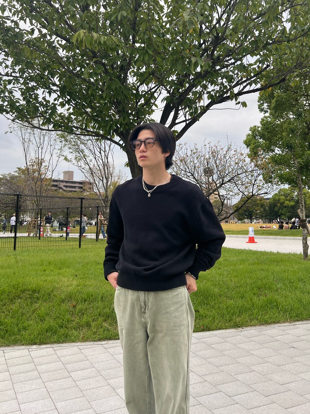 ブラック系のニット/セーター、ブラック系のチノパンツ、グレー系のスニーカーを着用したメンズの春コーディネートの2枚目の写真