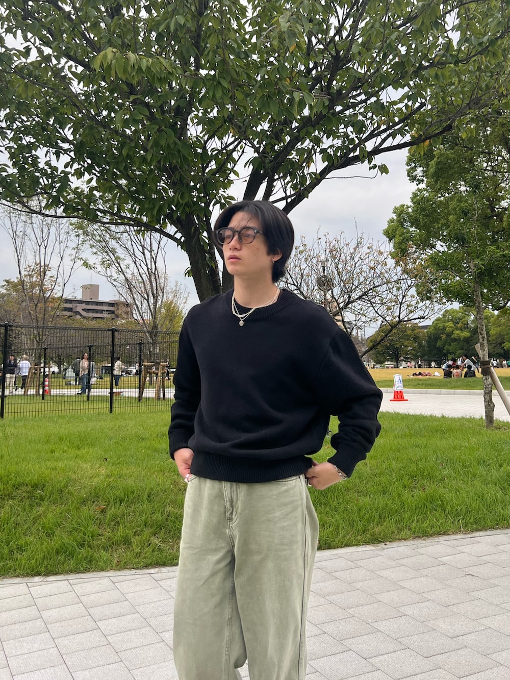 ブラック系のニット/セーター、ブラック系のチノパンツ、グレー系のスニーカーを着用したメンズの春コーディネートの5枚目の写真