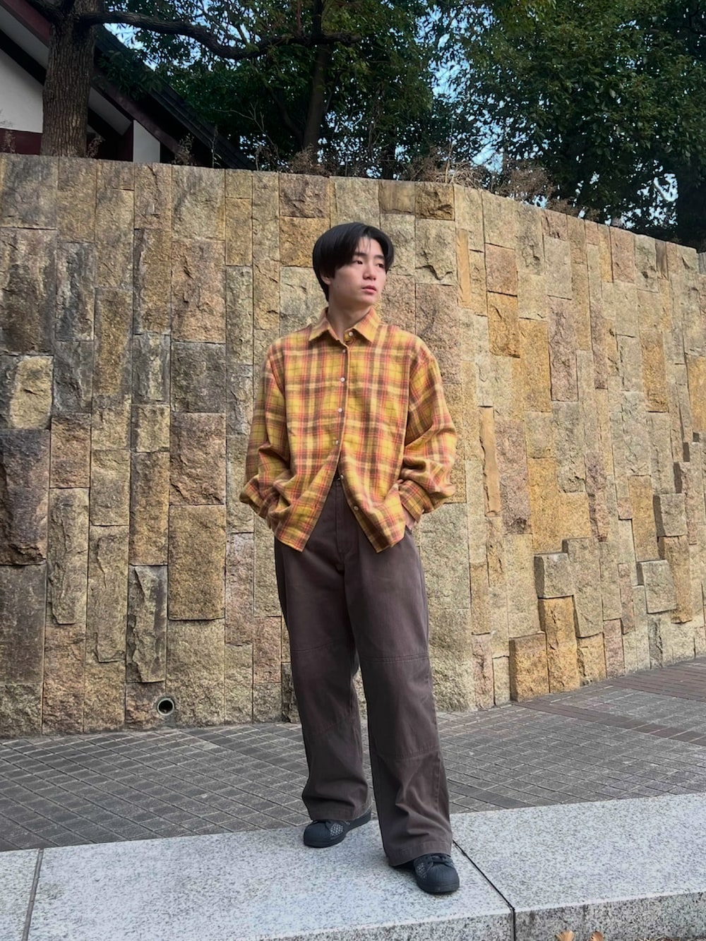 イエロー系のシャツ/ブラウス、ブラウン系のチノパンツ、ブラック系のスニーカーを着用したメンズの春コーディネートの2枚目の写真