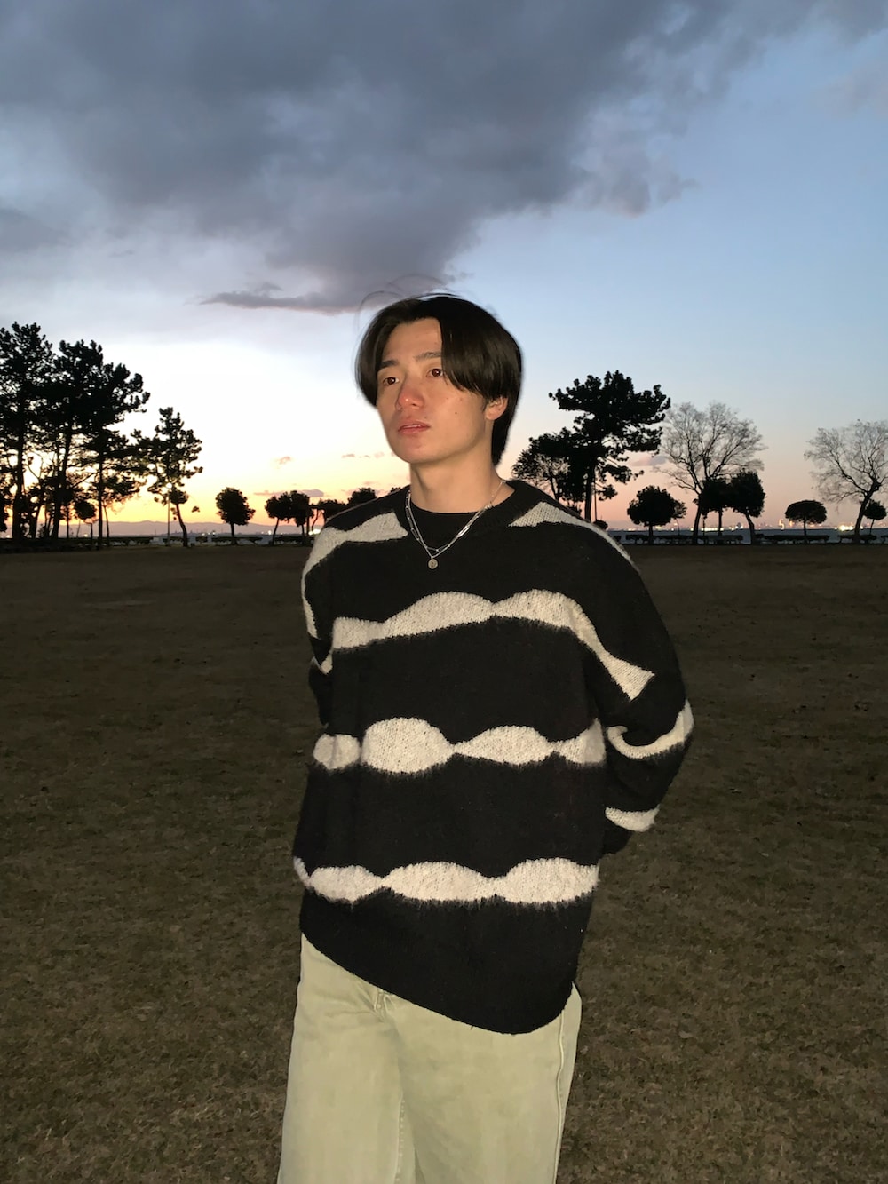 ブラック系のニット/セーター、グリーン系のチノパンツ、ホワイト系のスニーカーを着用したメンズの春コーディネートの4枚目の写真