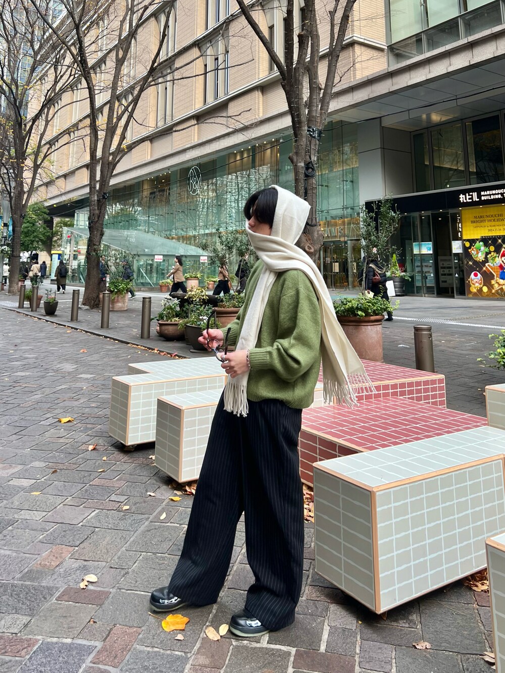 ブラック系のスラックス、グリーン系のニット/セーター、ブラック系のスニーカーを着用したメンズの春コーディネートの2枚目の写真