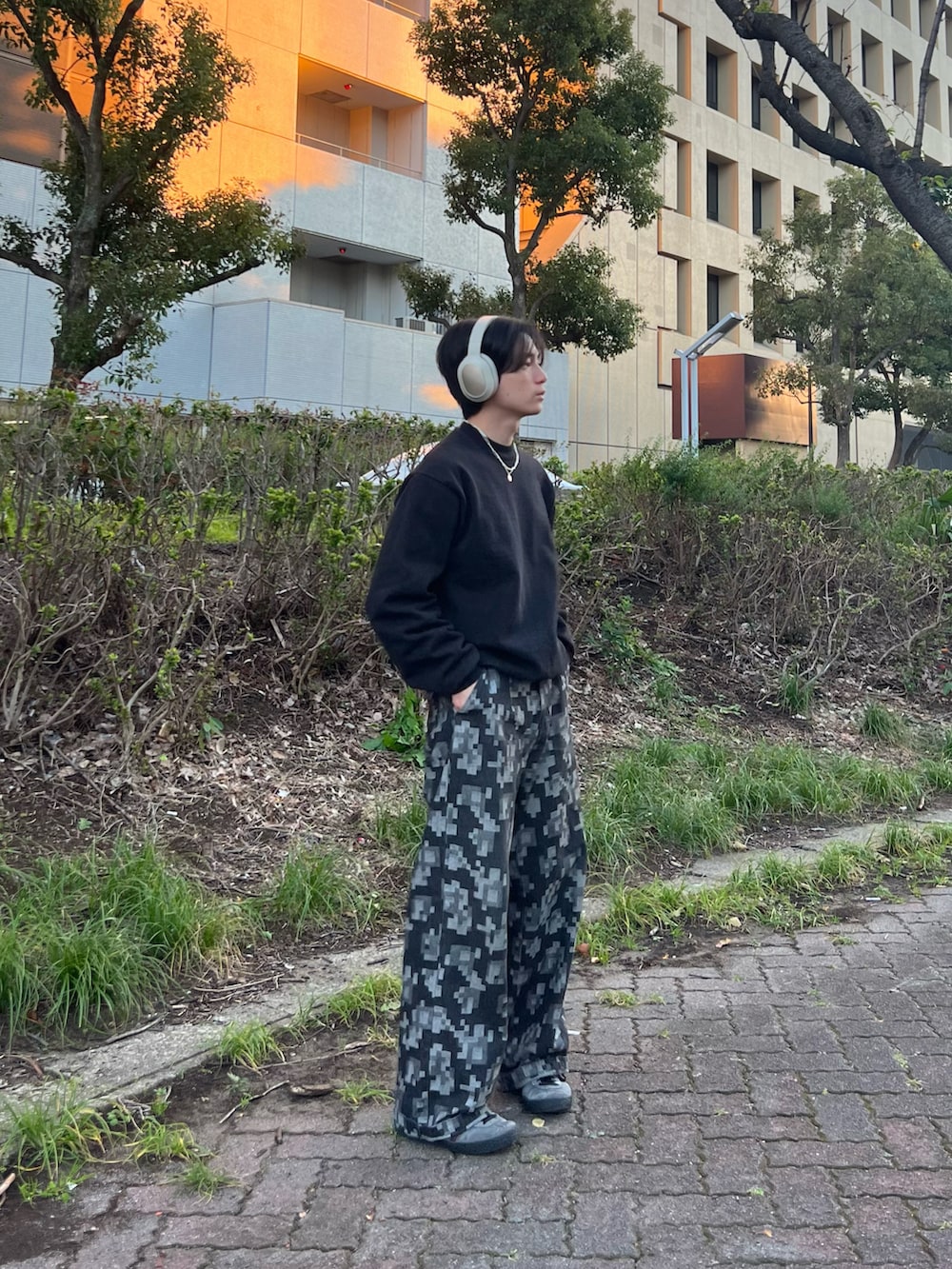 ブラック系のスウェット、ブラック系のチノパンツ、グレー系のスニーカーを着用したメンズの春コーディネートの2枚目の写真