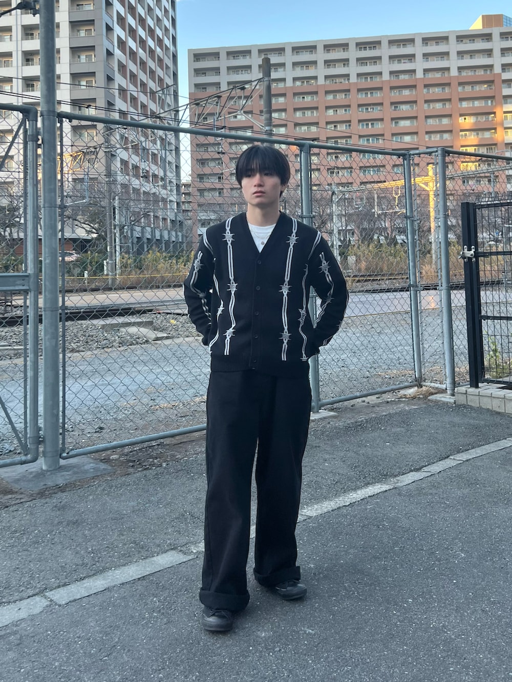 ブラック系のカーディガン/ボレロ、ブラック系のチノパンツ、ブラック系のスニーカーを着用したメンズの春コーディネートの2枚目の写真