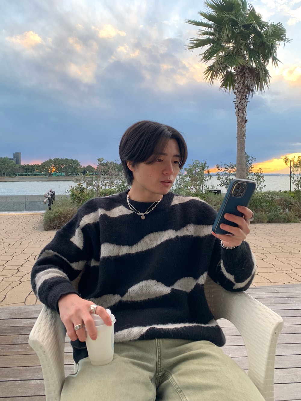 ブラック系のニット/セーター、グリーン系のチノパンツ、ホワイト系のスニーカーを着用したメンズの春コーディネートの5枚目の写真