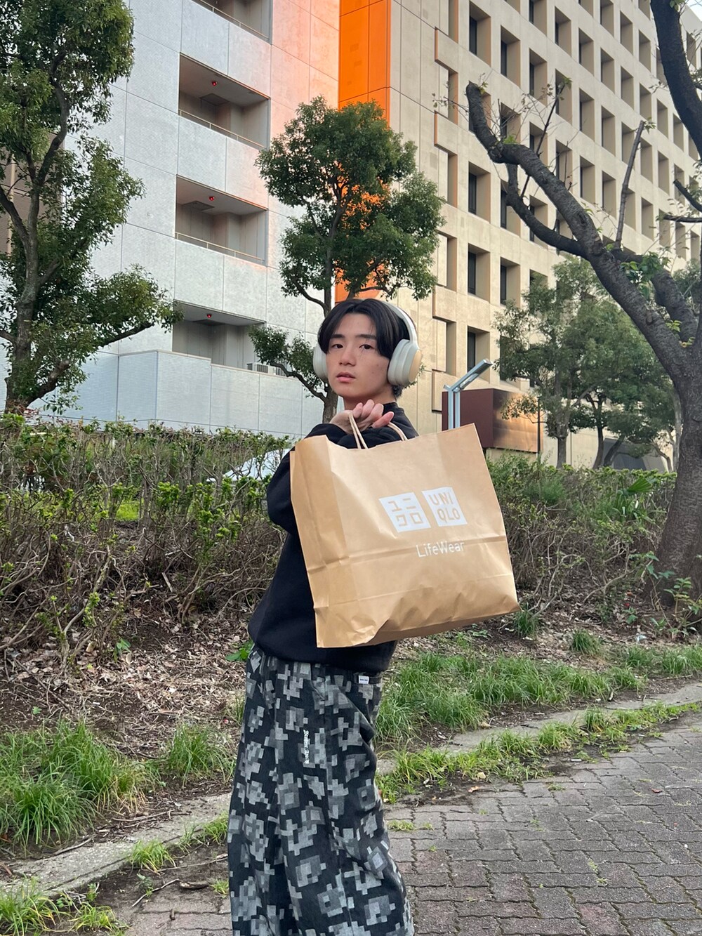 ブラック系のスウェット、ブラック系のチノパンツ、グレー系のスニーカーを着用したメンズの春コーディネートの5枚目の写真