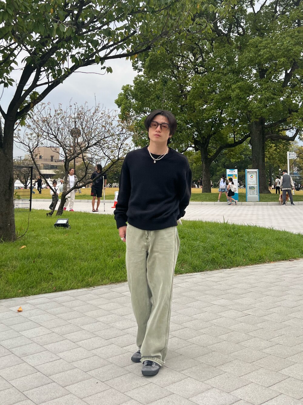 ブラック系のニット/セーター、ブラック系のチノパンツ、グレー系のスニーカーを着用したメンズの春コーディネートの3枚目の写真