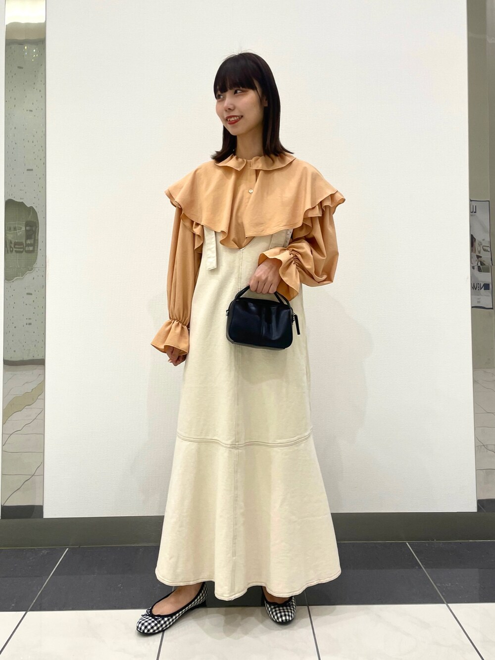ブラック系のバレエシューズ、ホワイト系のジャンパースカート、オレンジ系のシャツ/ブラウスを着用したレディースの春コーディネートの2枚目の写真