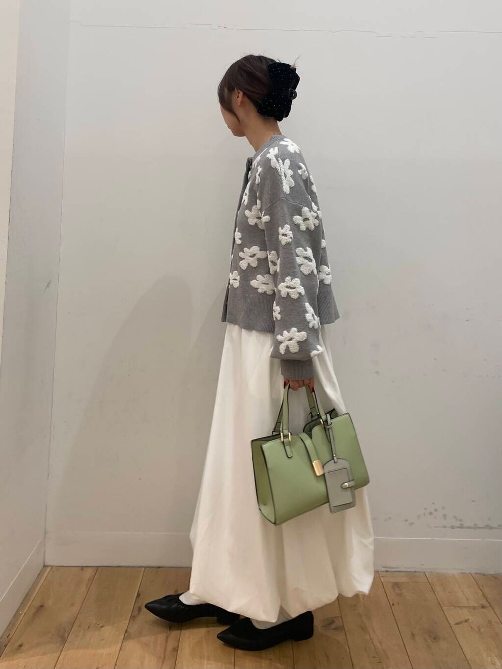 ホワイト系のスカート、ブラック系のパンプス、グレー系のカーディガン/ボレロを着用したレディースの冬コーディネートの2枚目の写真