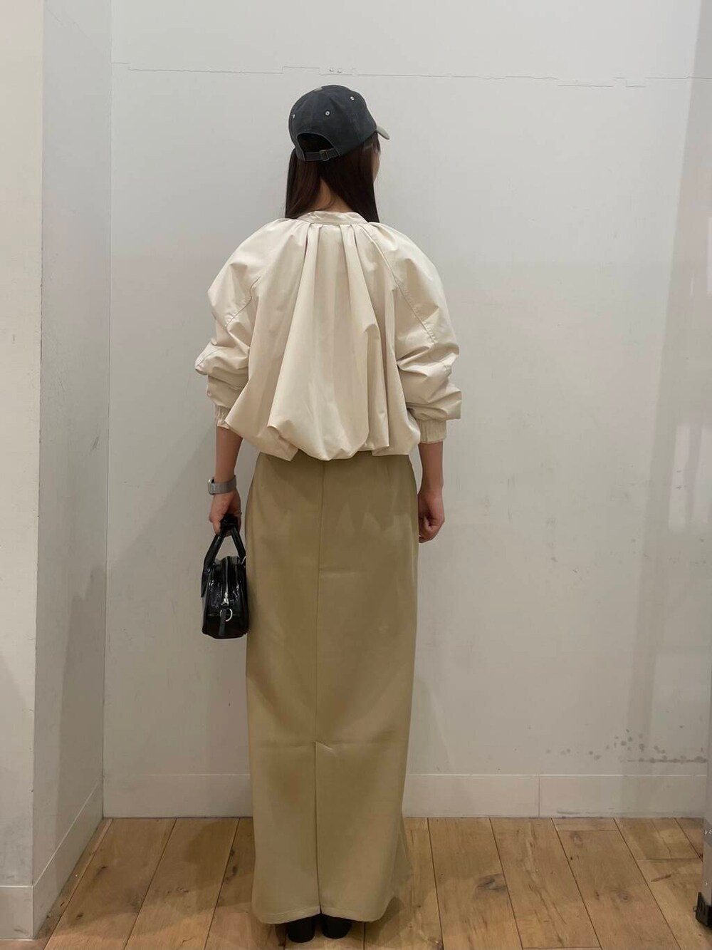 ブラック系のブーツ、ブラック系のボストンバッグ、ベージュ系のスカートを着用したレディースの冬コーディネートの3枚目の写真