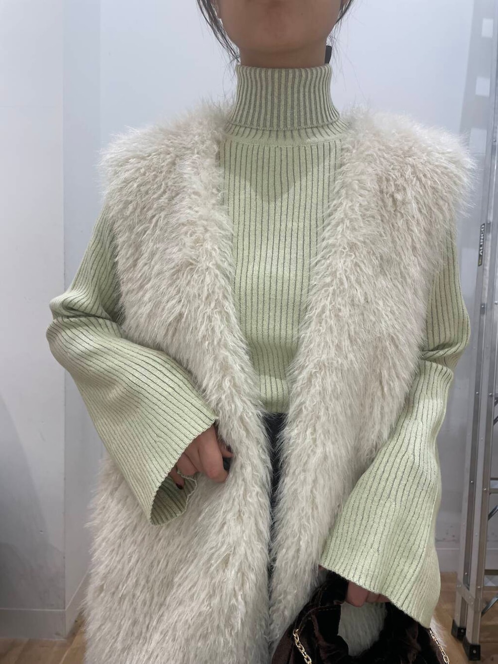 イエロー系のニット/セーター、グレー系のスカート、ブラウン系のハンドバッグを着用したレディースの秋コーディネートの4枚目の写真