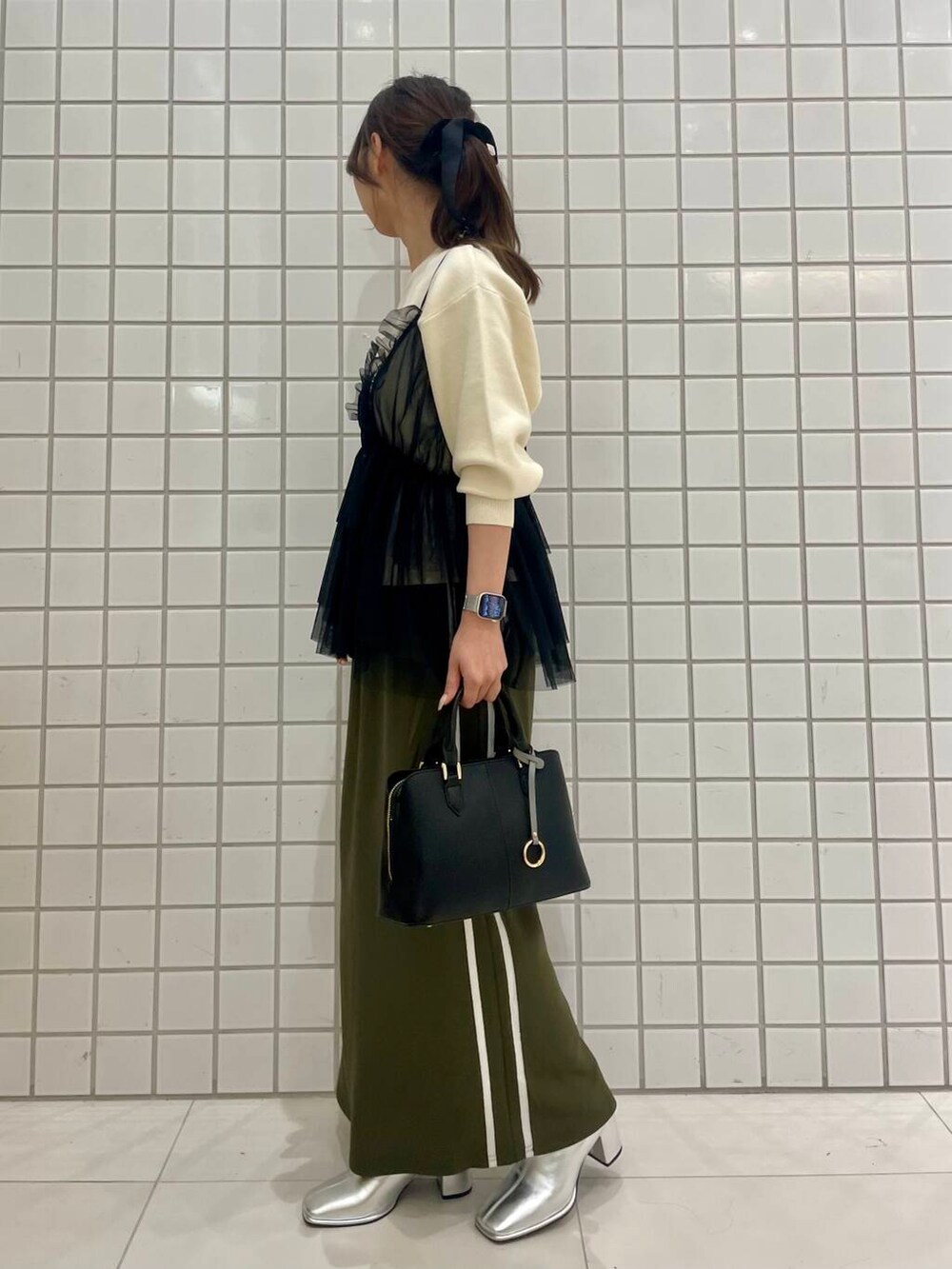 グリーン系のスカート、シルバー系のブーツ、ブラック系のキャミソールを着用したレディースの秋コーディネートの2枚目の写真