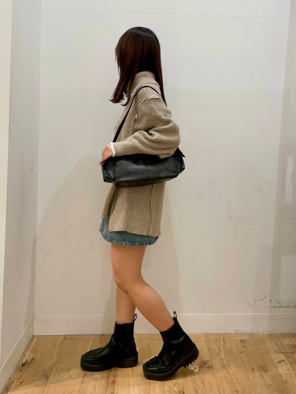 ベージュ系のニット/セーター、グレー系のハンドバッグ、ブルー系のスカートを着用したレディースの秋コーディネートの2枚目の写真