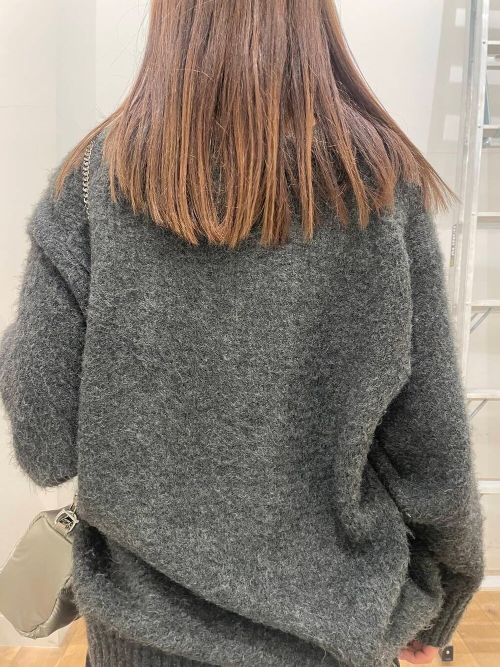 グレー系のニット/セーター、シルバー系のショルダーバッグを着用したレディースの冬コーディネートの5枚目の写真