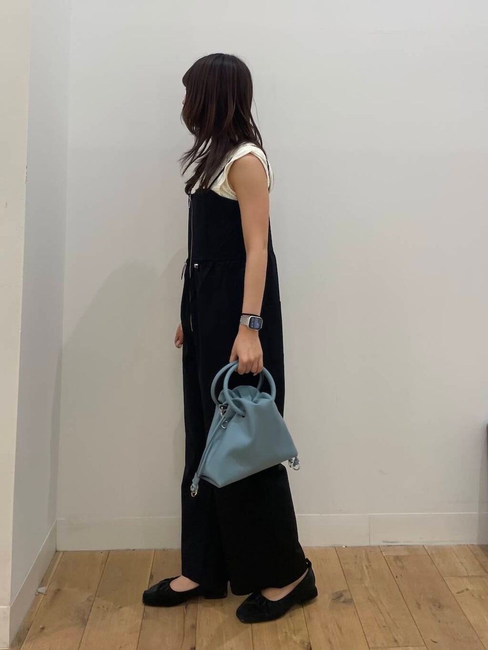 ブルー系のハンドバッグ、ブラック系のサロペット/オーバーオール、ホワイト系のTシャツ/カットソーを着用したレディースの夏コーディネートの2枚目の写真