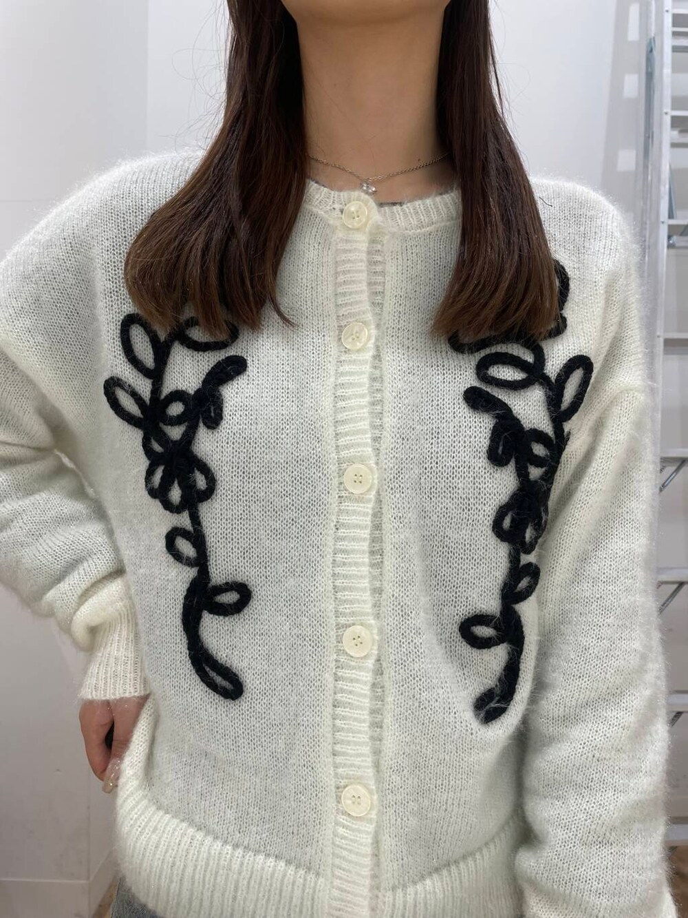 ホワイト系のカーディガン/ボレロ、ブルー系のデニムパンツ、ブラック系のハンドバッグを着用したレディースの冬コーディネートの4枚目の写真