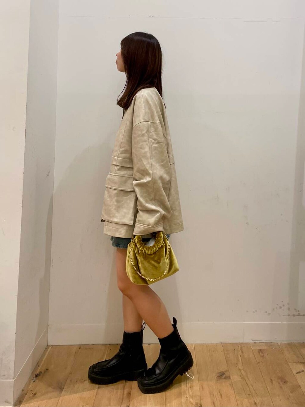 イエロー系のハンドバッグ、ブルー系のスカート、ホワイト系のその他アウターを着用したレディースの秋コーディネートの2枚目の写真