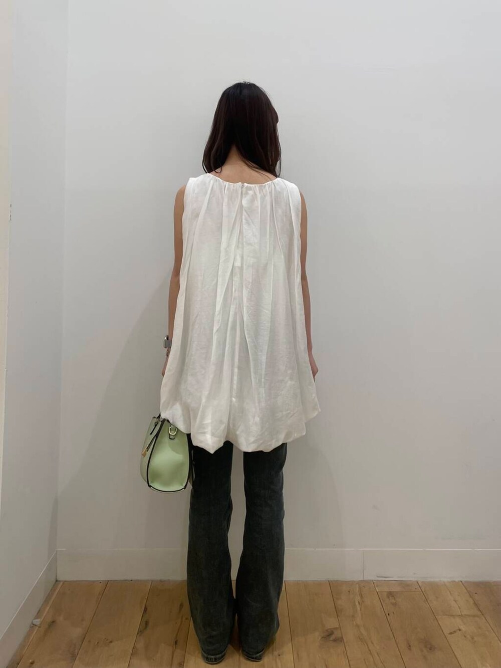 グリーン系のハンドバッグ、シルバー系のサンダル、ブルー系のデニムパンツを着用したレディースの春コーディネートの3枚目の写真