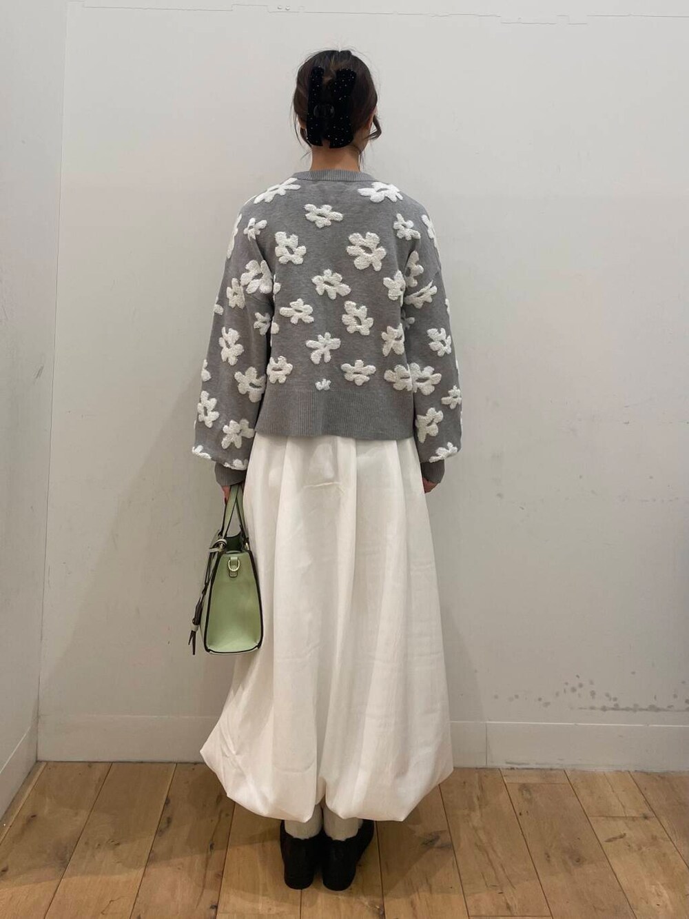 ホワイト系のスカート、ブラック系のパンプス、グレー系のカーディガン/ボレロを着用したレディースの冬コーディネートの3枚目の写真