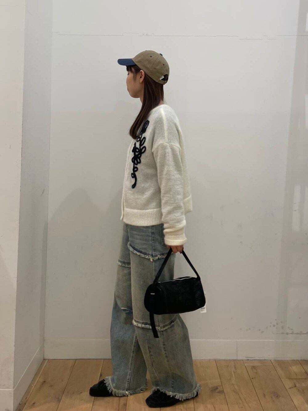 ホワイト系のカーディガン/ボレロ、ブルー系のデニムパンツ、ブラック系のハンドバッグを着用したレディースの冬コーディネートの2枚目の写真