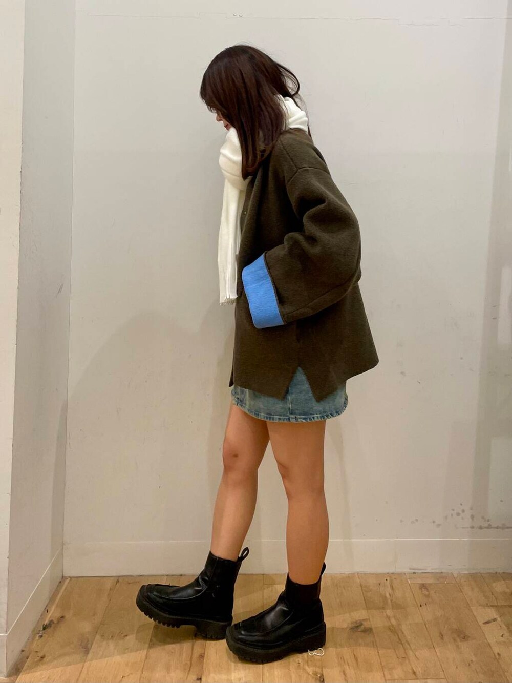 ブルー系のスカート、ブラウン系のその他アウター、ホワイト系のマフラーを着用したレディースの秋コーディネートの2枚目の写真