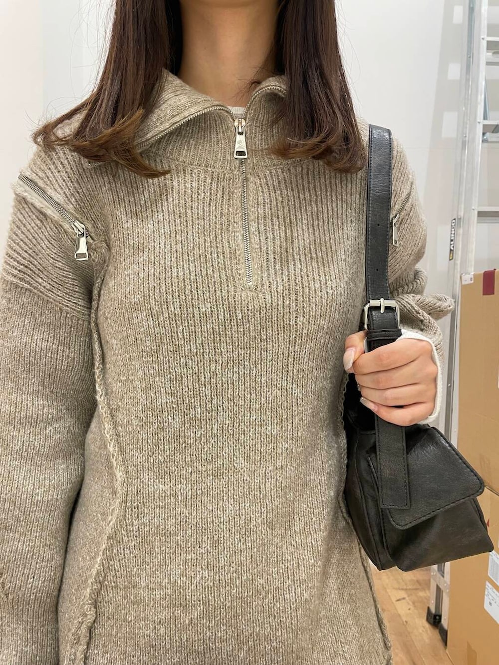 ベージュ系のニット/セーター、グレー系のハンドバッグ、ブルー系のスカートを着用したレディースの秋コーディネートの4枚目の写真