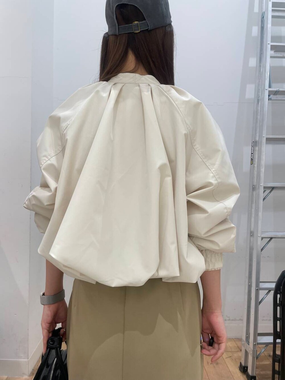 ブラック系のブーツ、ブラック系のボストンバッグ、ベージュ系のスカートを着用したレディースの冬コーディネートの5枚目の写真