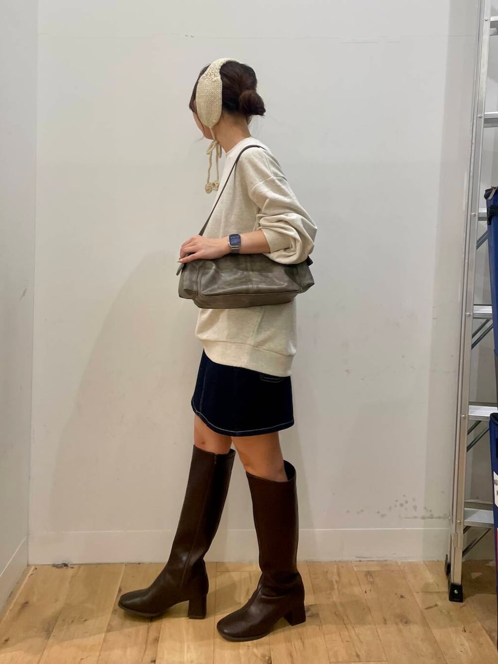ブラウン系のブーツ、グレー系のハンドバッグ、ブルー系のスカートを着用したレディースの秋コーディネートの2枚目の写真
