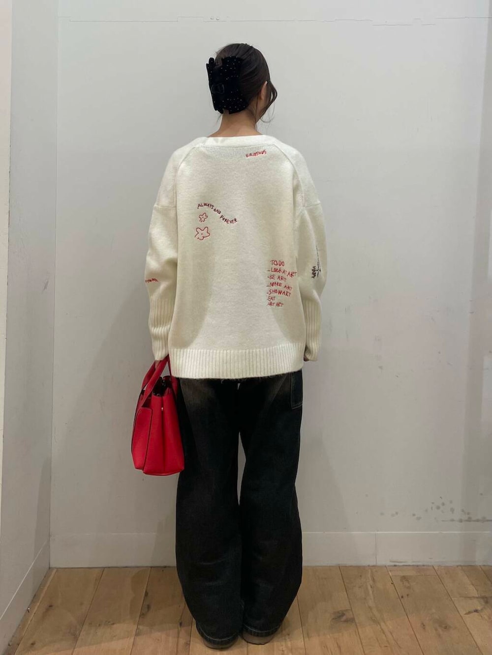 レッド系のトートバッグ、ホワイト系のTシャツ/カットソー、ホワイト系のカーディガン/ボレロを着用したレディースの冬コーディネートの3枚目の写真