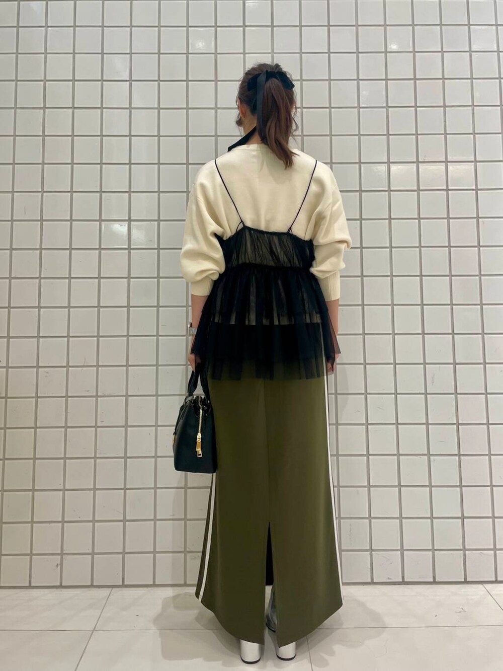 グリーン系のスカート、シルバー系のブーツ、ブラック系のキャミソールを着用したレディースの秋コーディネートの3枚目の写真