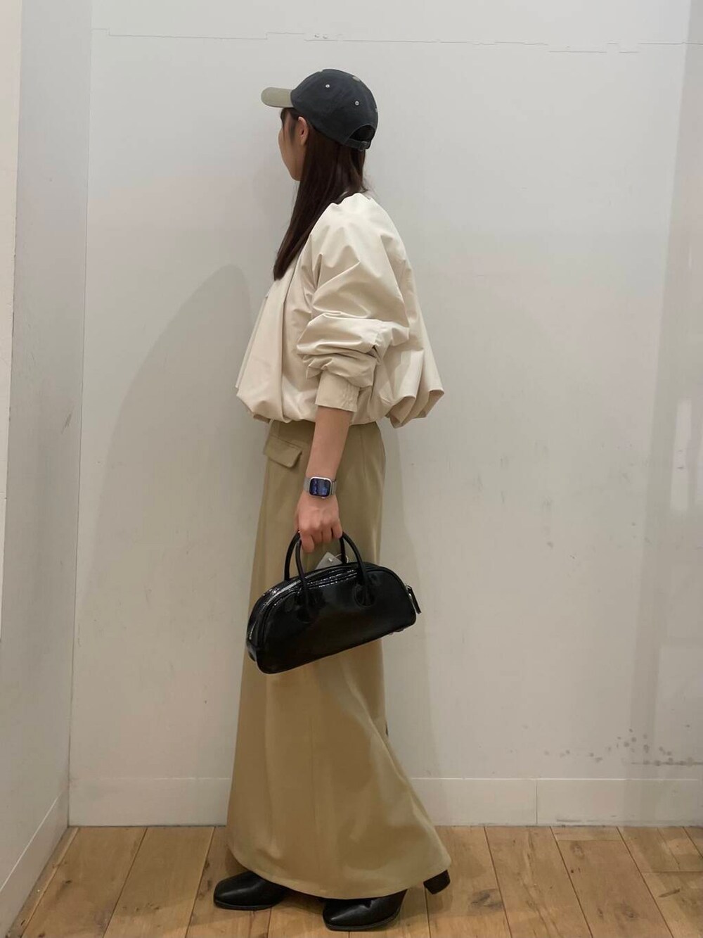 ブラック系のブーツ、ブラック系のボストンバッグ、ベージュ系のスカートを着用したレディースの冬コーディネートの2枚目の写真