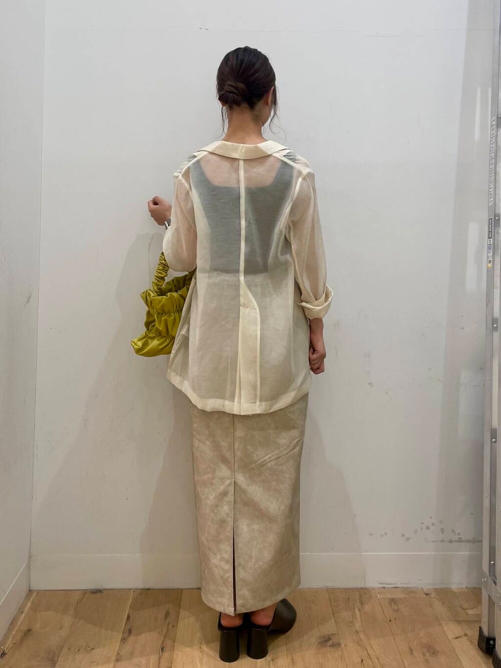 イエロー系のハンドバッグ、ブラック系のTシャツ/カットソー、ブラック系のサンダルを着用したレディースの秋コーディネートの3枚目の写真