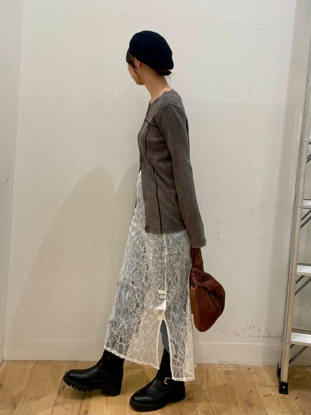 ブラック系のブーツ、ブルー系のデニムパンツ、ブラウン系のハンドバッグを着用したレディースの秋コーディネートの2枚目の写真