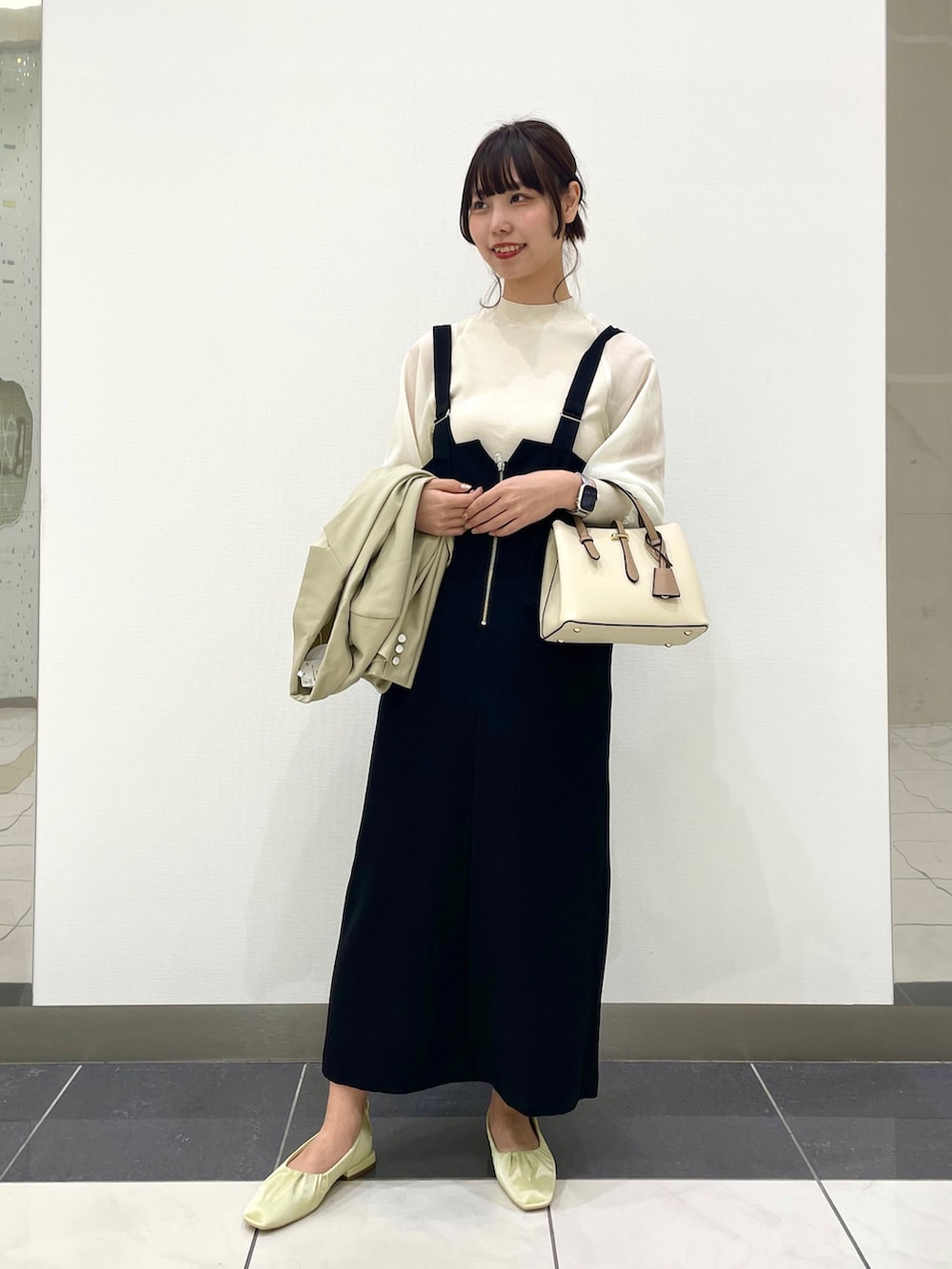 イエロー系のパンプス、ブラック系のワンピース、ホワイト系のハンドバッグを着用したレディースの春コーディネートの2枚目の写真