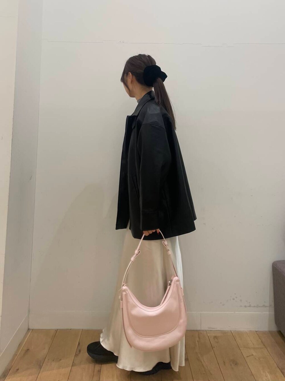 ピンク系のショルダーバッグ、ホワイト系のベスト、ブラック系のその他アウターを着用したレディースの冬コーディネートの2枚目の写真