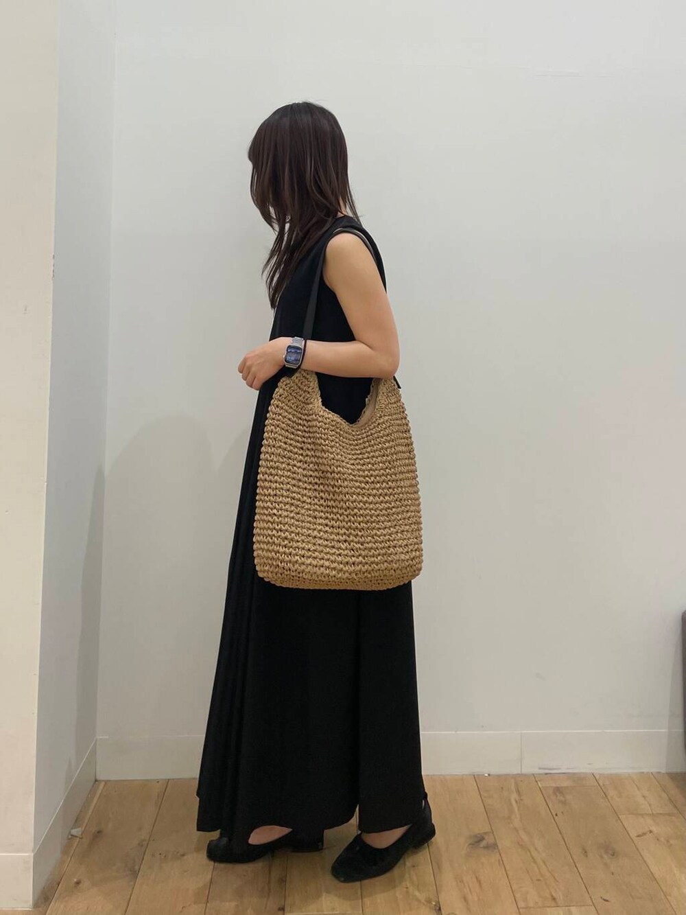 イエロー系のトートバッグ、ブラック系のワンピースを着用したレディースの春コーディネートの2枚目の写真