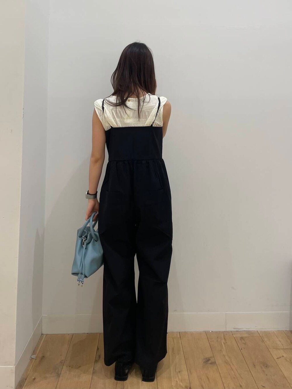 ブルー系のハンドバッグ、ブラック系のサロペット/オーバーオール、ホワイト系のTシャツ/カットソーを着用したレディースの夏コーディネートの3枚目の写真