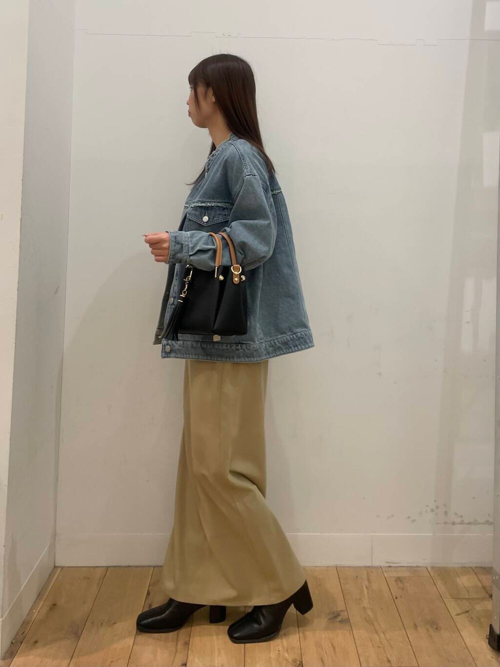 ブラック系のトートバッグ、ブラック系のブーツ、ベージュ系のスカートを着用したレディースの冬コーディネートの2枚目の写真
