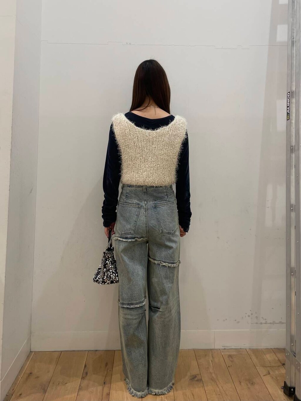 シルバー系のショルダーバッグ、ブルー系のTシャツ/カットソー、ブルー系のデニムパンツを着用したレディースの冬コーディネートの3枚目の写真