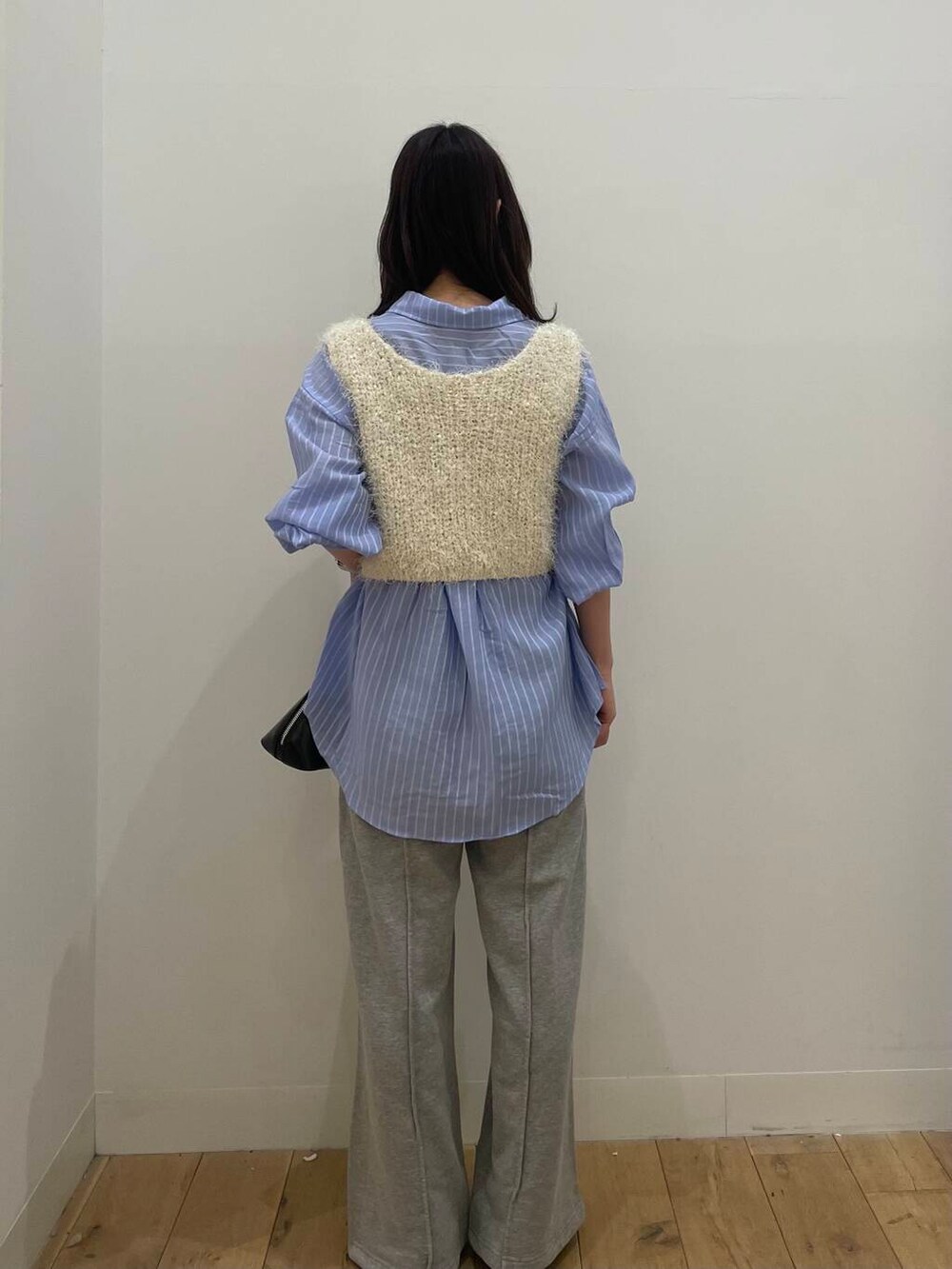 ブラック系のボストンバッグ、ホワイト系のベスト、ブルー系のシャツ/ブラウスを着用したレディースの春コーディネートの3枚目の写真