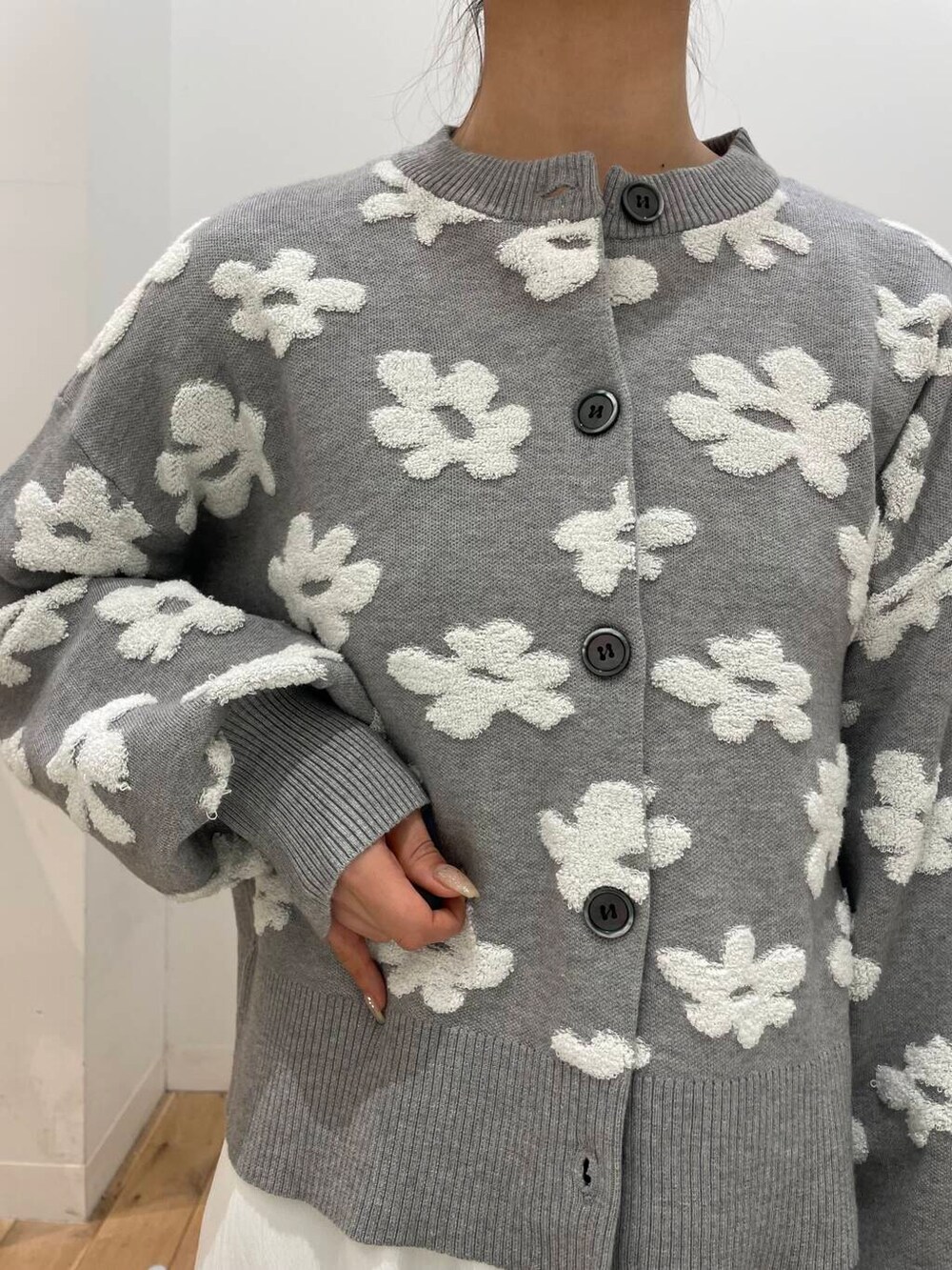 ホワイト系のスカート、ブラック系のパンプス、グレー系のカーディガン/ボレロを着用したレディースの冬コーディネートの4枚目の写真