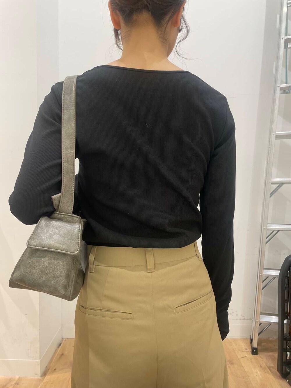 グレー系のハンドバッグ、ゴールド系のブーツ、ブラック系のTシャツ/カットソーを着用したレディースの秋コーディネートの5枚目の写真