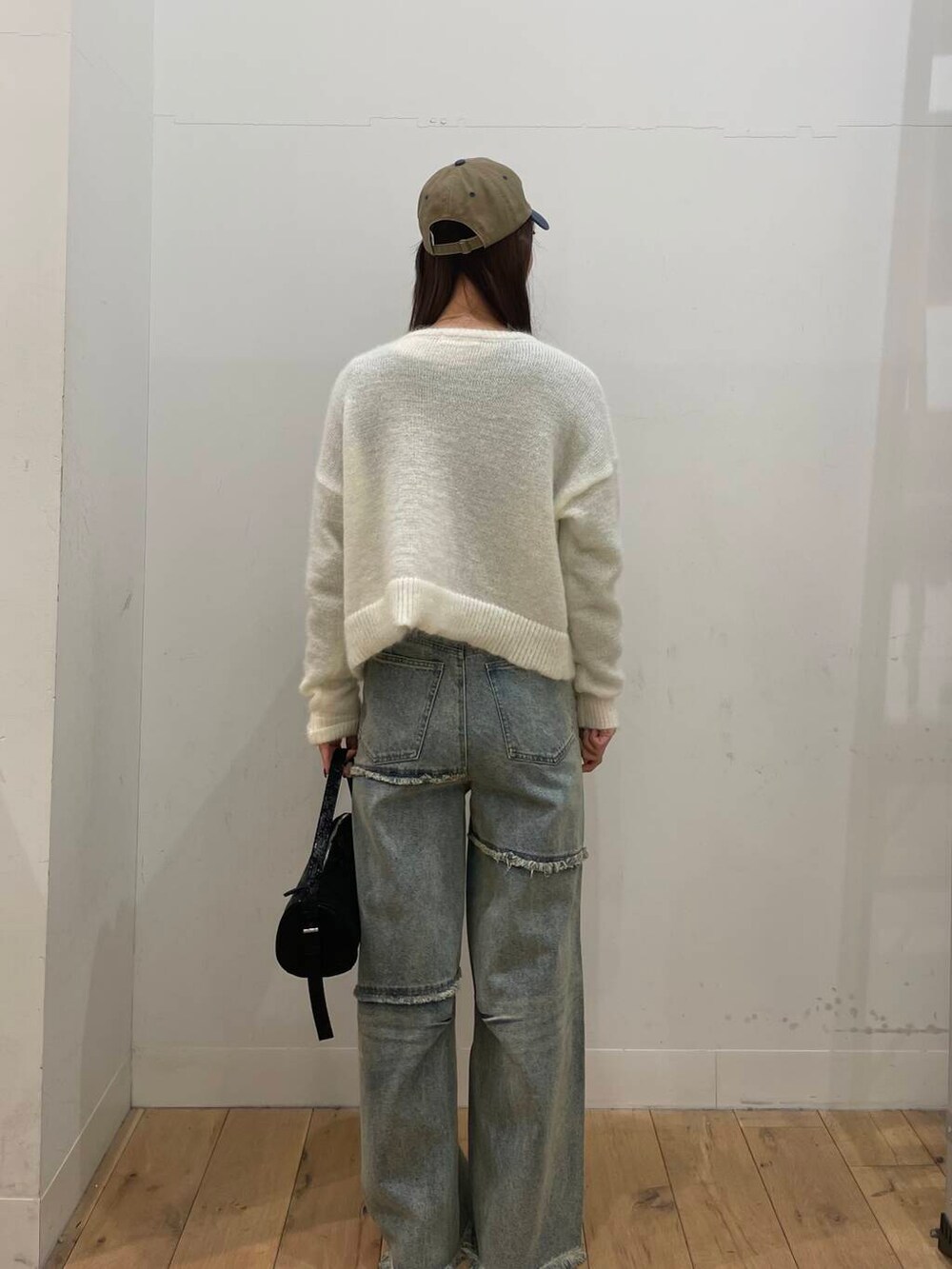 ホワイト系のカーディガン/ボレロ、ブルー系のデニムパンツ、ブラック系のハンドバッグを着用したレディースの冬コーディネートの3枚目の写真