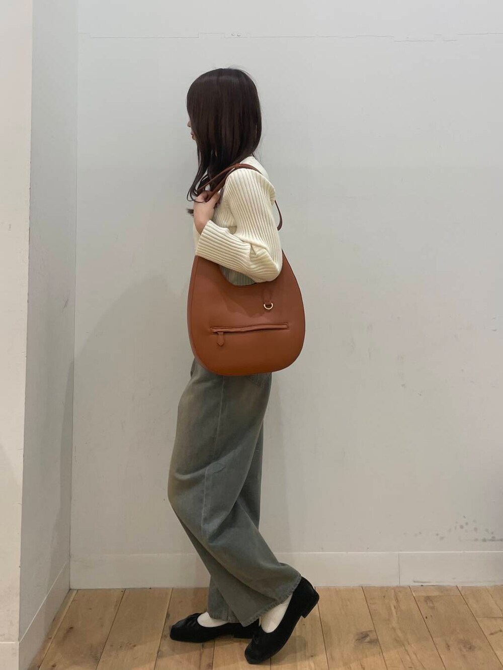 ブラウン系のショルダーバッグ、ホワイト系のニット/セーター、ブラウン系のデニムパンツを着用したレディースの春コーディネートの2枚目の写真