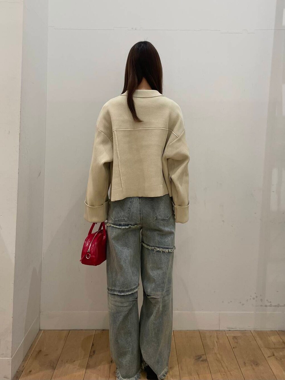 レッド系のボストンバッグ、ブルー系のデニムパンツ、ホワイト系のその他アウターを着用したレディースの冬コーディネートの3枚目の写真