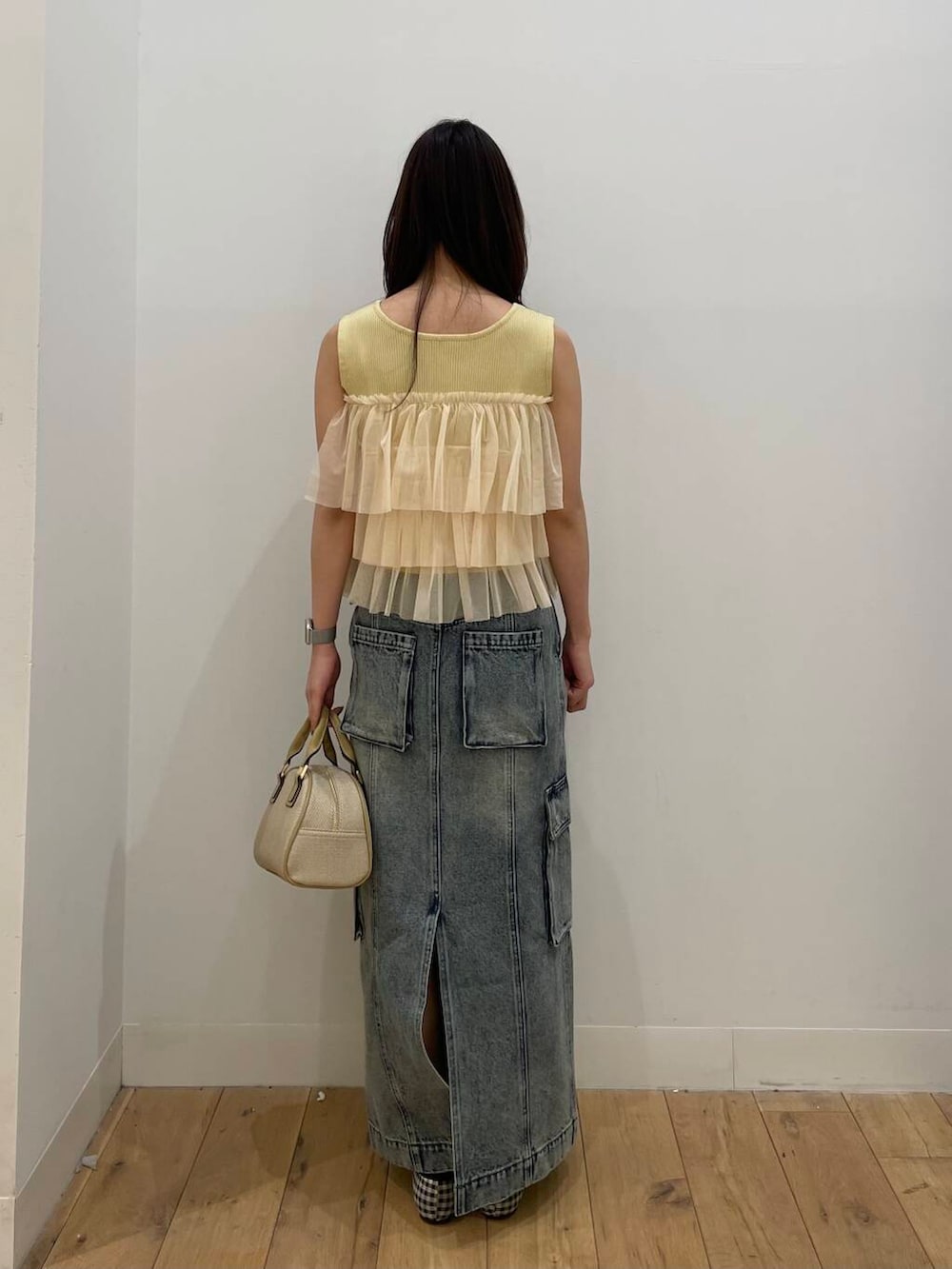 ベージュ系のボストンバッグ、ブルー系のスカート、イエロー系のニット/セーターを着用したレディースの春コーディネートの3枚目の写真