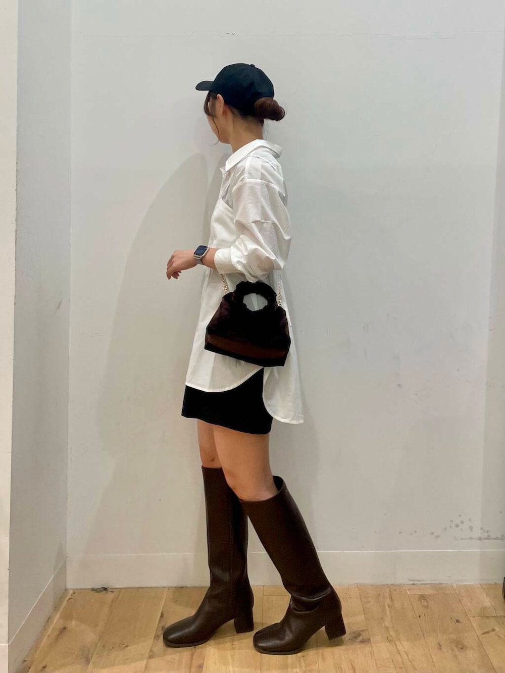 ブラウン系のハンドバッグ、ブラウン系のブーツ、ホワイト系のシャツ/ブラウスを着用したレディースの秋コーディネートの2枚目の写真