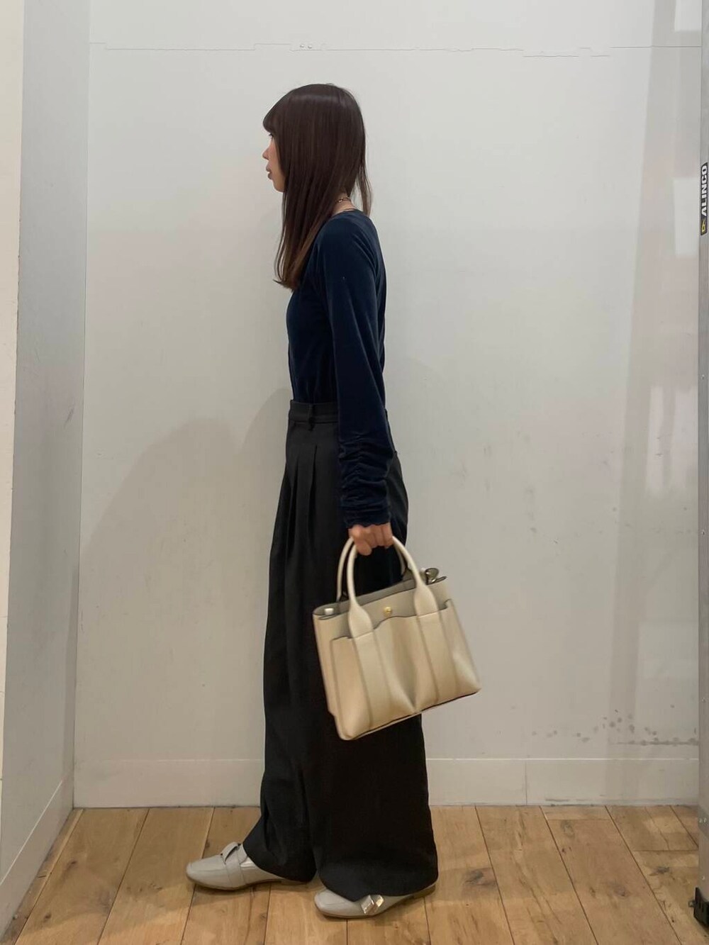 ホワイト系のトートバッグ、グレー系のその他パンツ、ブルー系のTシャツ/カットソーを着用したレディースの冬コーディネートの2枚目の写真